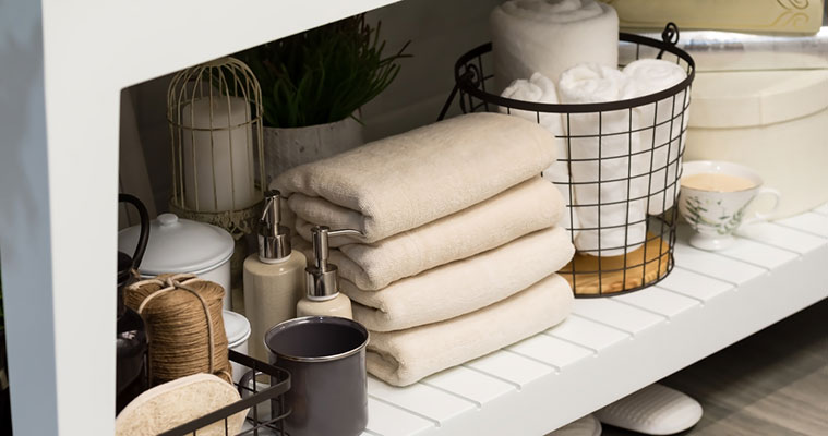 spacio ordenado debajo del lavabo del baño con cestas, toallas dobladas y dispensadores de jabón, ejemplo de organización eficiente