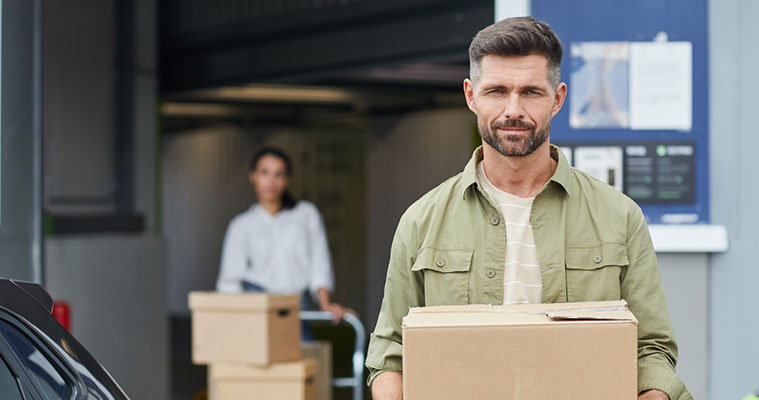 Man and woman moving boxes out of a self storage unit in Barcelona, illustrating furniture storage rental