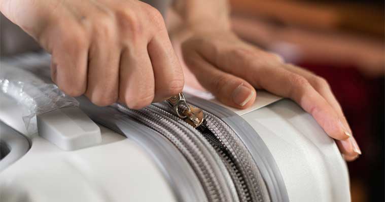 Primer plano de una persona abriendo o cerrando una maleta, representando el almacenamiento de equipaje tras el verano en Madrid