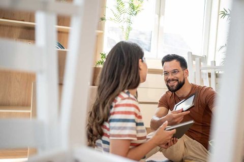 Smiling couple unpacking framed photos while settling into a new home, supported by OhMyBox storage.