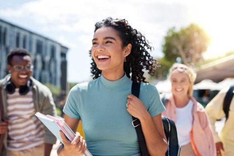 Smiling student walking with books and backpack, representing flexible OhMyBox storage for studying abroad or moving.